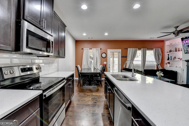 kitchen featuring stainless steel appliances, a sink, light countertops, decorative backsplash, and dark wood finished floors