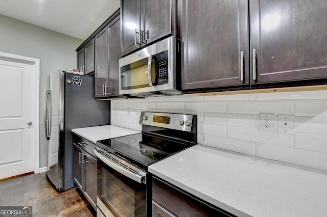 kitchen featuring appliances with stainless steel finishes, dark wood-type flooring, dark brown cabinetry, and decorative backsplash