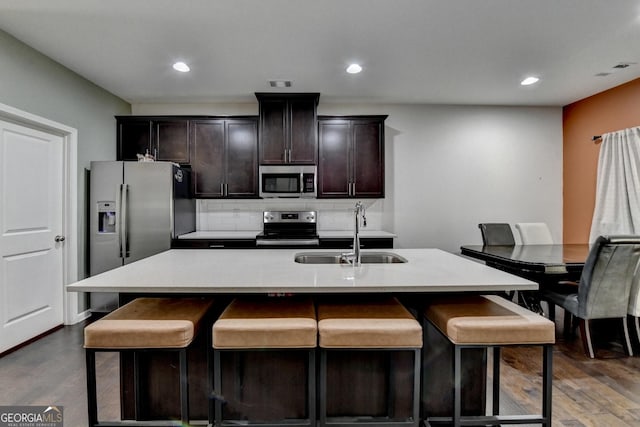 kitchen with an island with sink, stainless steel appliances, a sink, and light countertops