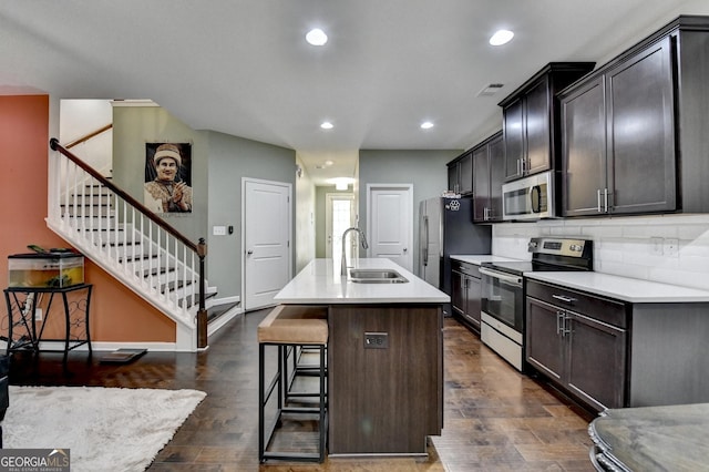 kitchen featuring a breakfast bar, light countertops, appliances with stainless steel finishes, a kitchen island with sink, and a sink