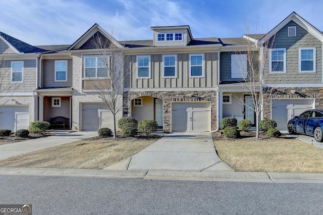 multi unit property featuring board and batten siding, stone siding, driveway, and an attached garage