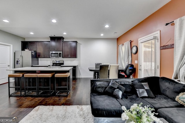 living area with baseboards, dark wood-type flooring, and recessed lighting