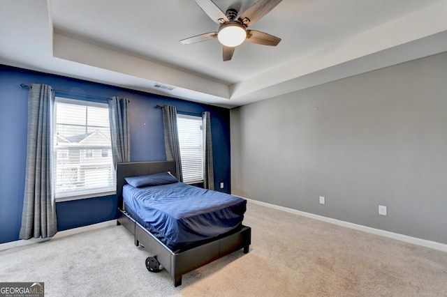 bedroom featuring a tray ceiling, baseboards, and carpet flooring