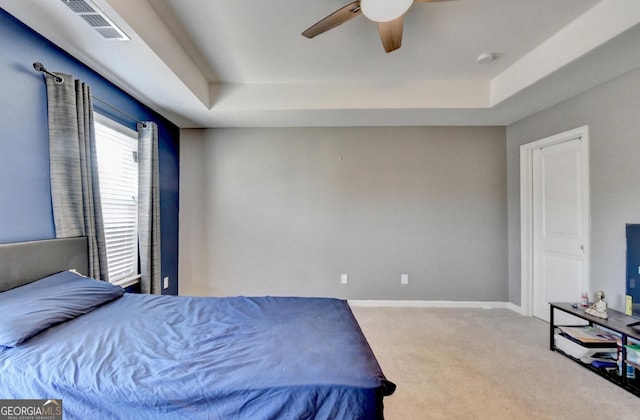 bedroom featuring a tray ceiling, visible vents, light carpet, and baseboards