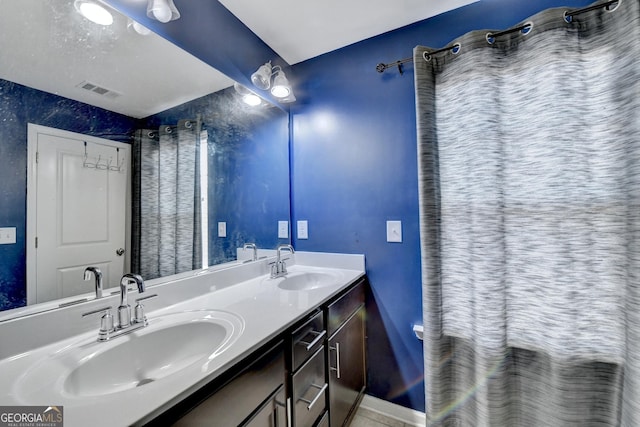 bathroom featuring double vanity, a sink, visible vents, and baseboards