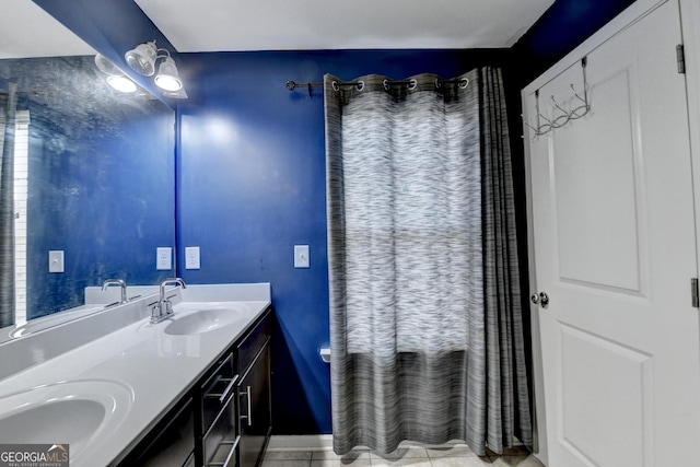 bathroom with double vanity, tile patterned flooring, a sink, and baseboards