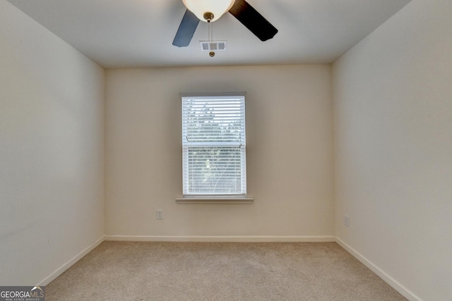 empty room featuring a ceiling fan, visible vents, light carpet, and baseboards