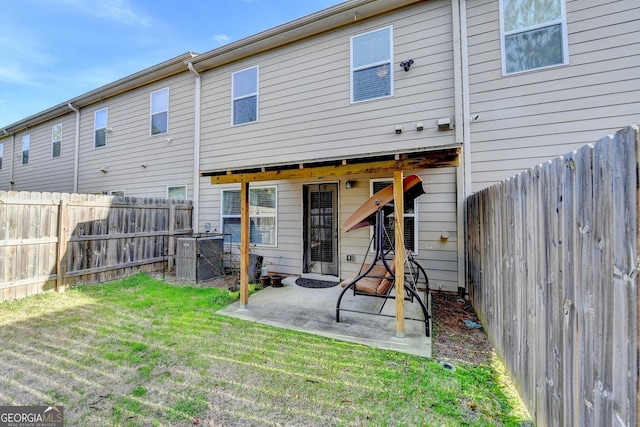 rear view of house with a fenced backyard, a patio, and a lawn