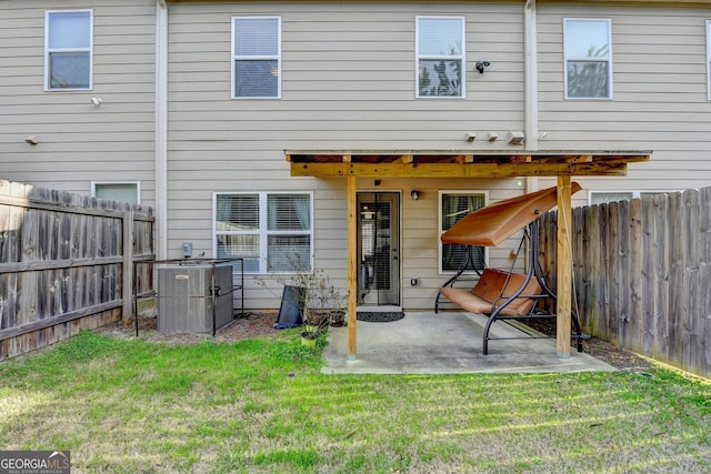 back of property with a fenced backyard, a yard, central AC, and a patio