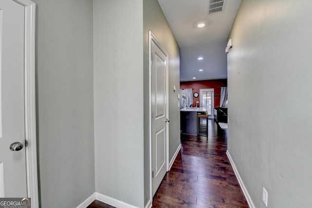 hallway featuring dark wood-style flooring, recessed lighting, visible vents, and baseboards