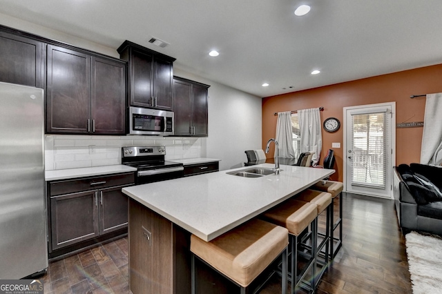 kitchen featuring a center island with sink, visible vents, stainless steel appliances, light countertops, and a sink