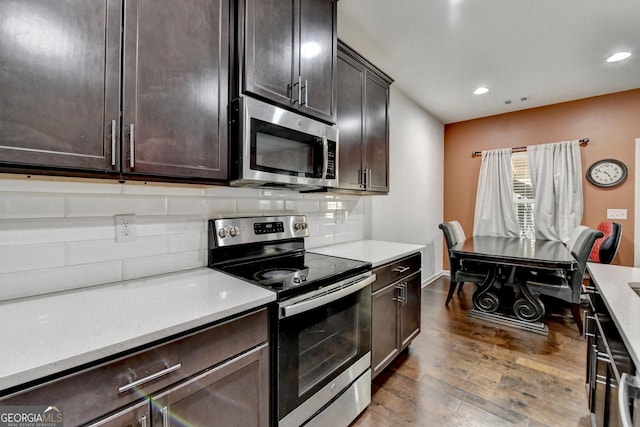 kitchen featuring stainless steel appliances, dark brown cabinets, light countertops, backsplash, and dark wood finished floors