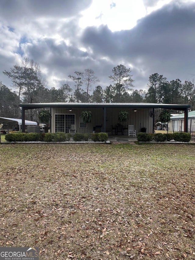 view of front of home with an attached carport, board and batten siding, and a front yard