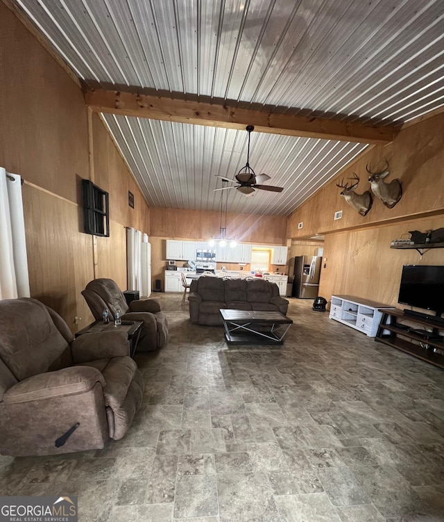 living area featuring wood walls, lofted ceiling with beams, and ceiling fan