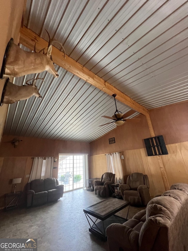 living room featuring concrete floors, vaulted ceiling with beams, wood walls, and ceiling fan