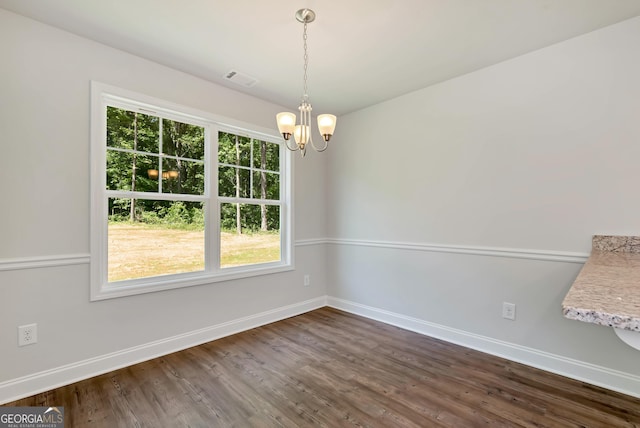 unfurnished dining area with dark wood-style floors, visible vents, baseboards, and an inviting chandelier