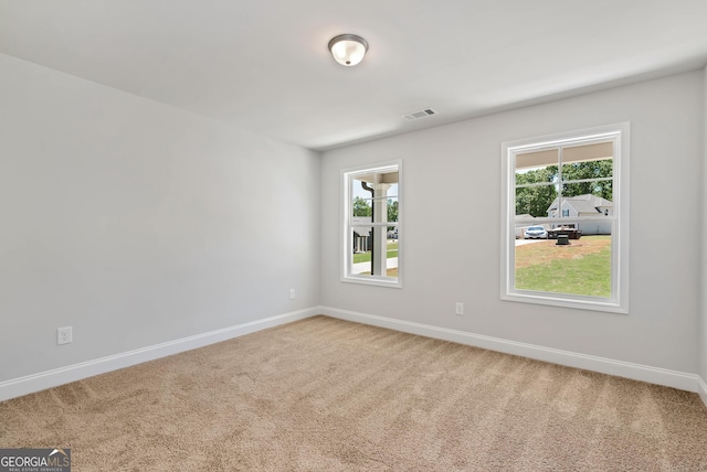 carpeted spare room featuring baseboards and visible vents