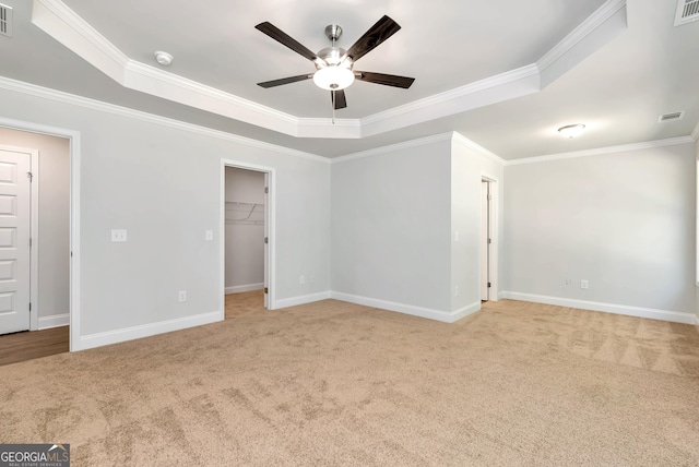 spare room featuring light colored carpet, visible vents, baseboards, ornamental molding, and a raised ceiling