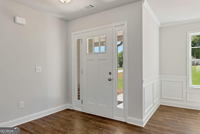 foyer with a wainscoted wall, crown molding, visible vents, and dark wood-style flooring