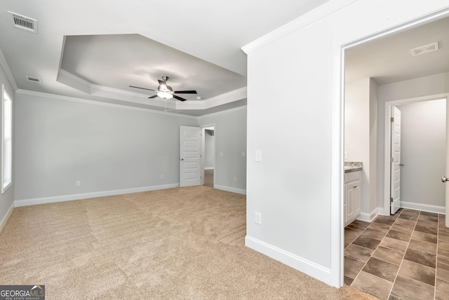 unfurnished bedroom with carpet, baseboards, a raised ceiling, and crown molding