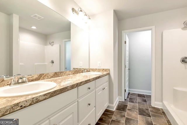 full bathroom with baseboards, visible vents, walk in shower, and a sink