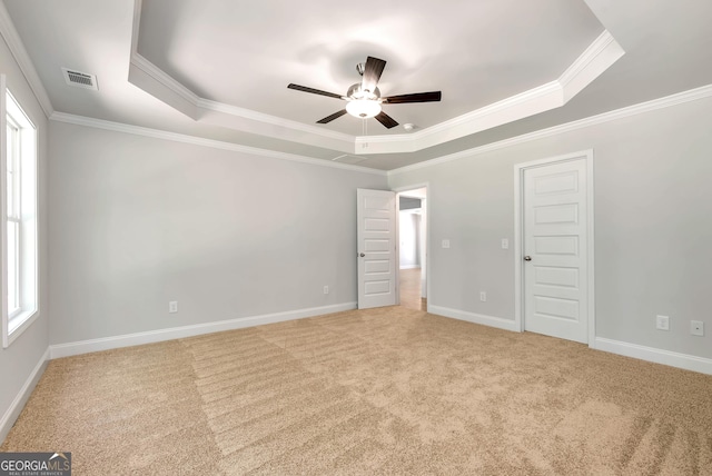 unfurnished bedroom with visible vents, baseboards, carpet, a tray ceiling, and crown molding