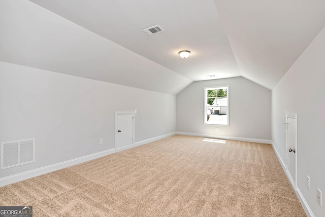 bonus room featuring light carpet, baseboards, visible vents, and vaulted ceiling