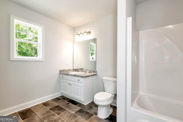 bathroom featuring a healthy amount of sunlight, baseboards, toilet, and vanity