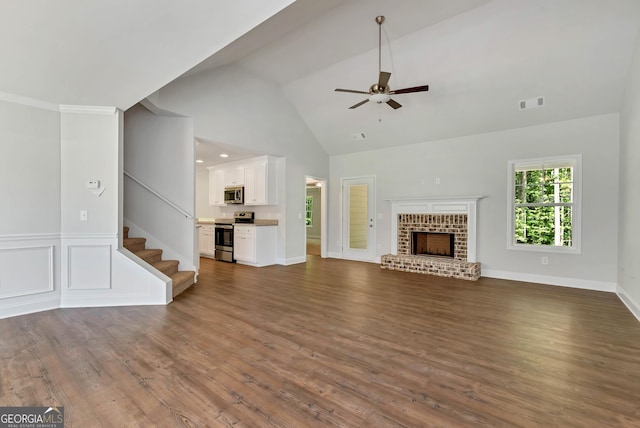 unfurnished living room with dark wood-style flooring, visible vents, a ceiling fan, stairway, and a brick fireplace