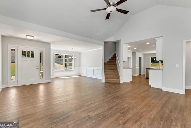 unfurnished living room with ceiling fan with notable chandelier, dark wood finished floors, plenty of natural light, and stairs