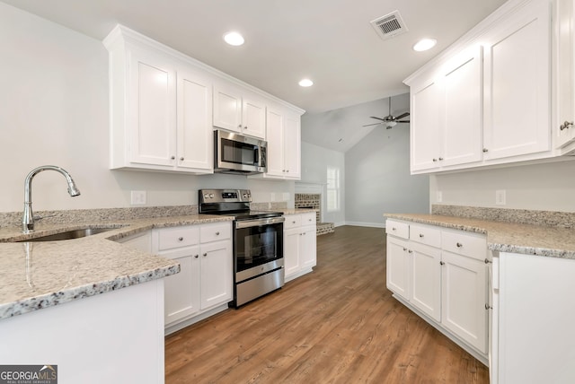 kitchen with a sink, visible vents, white cabinets, appliances with stainless steel finishes, and light stone countertops