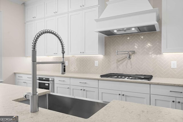 kitchen with light stone counters, white cabinetry, and custom exhaust hood