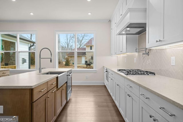 kitchen featuring light countertops, white cabinets, stainless steel gas stovetop, and custom exhaust hood