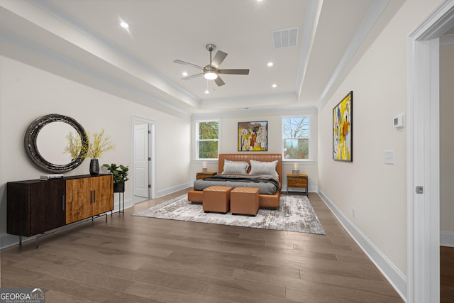 bedroom with baseboards, visible vents, dark wood finished floors, and a tray ceiling