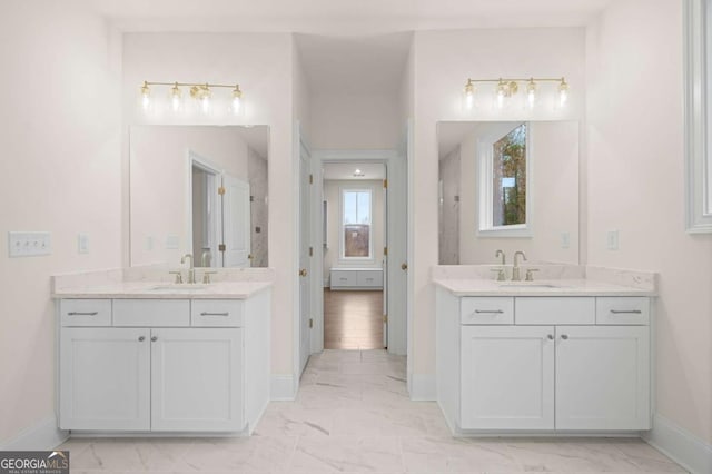 bathroom with marble finish floor, two vanities, and a sink