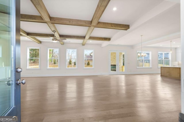 unfurnished living room featuring wood finished floors, coffered ceiling, beamed ceiling, baseboards, and ceiling fan with notable chandelier