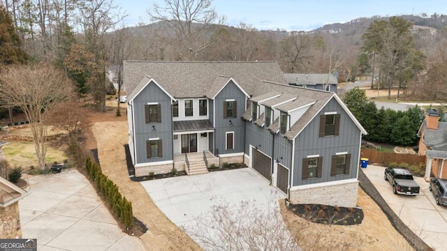 modern farmhouse featuring board and batten siding, concrete driveway, roof with shingles, and a mountain view