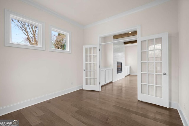 empty room featuring a large fireplace, baseboards, dark wood finished floors, and crown molding