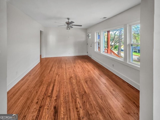 unfurnished living room with baseboards, visible vents, ceiling fan, and wood finished floors