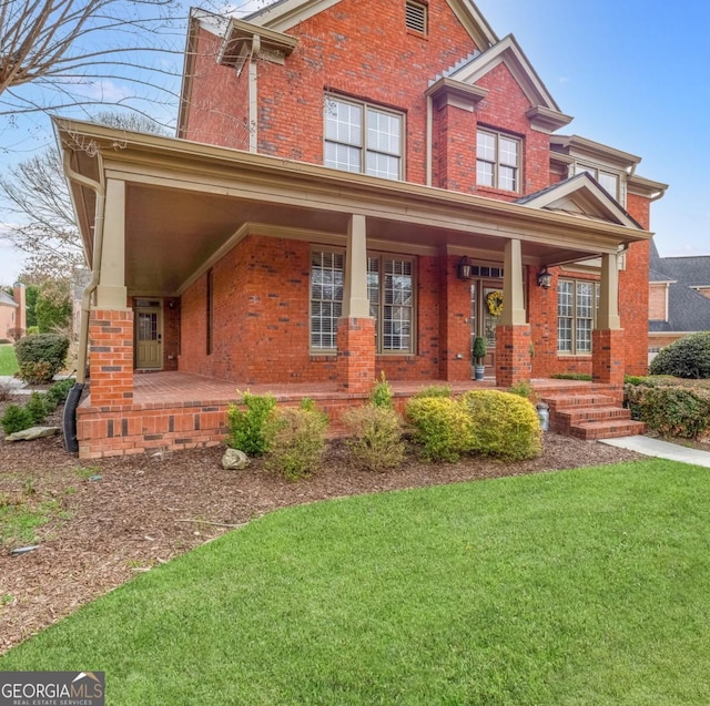 view of front of home with a front lawn, a porch, and brick siding