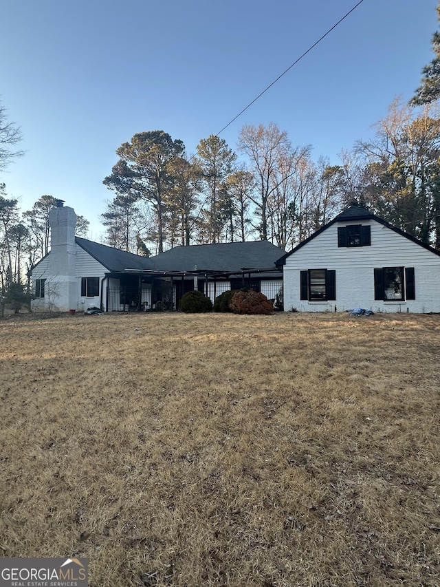 view of front of house with brick siding, a chimney, and a front yard