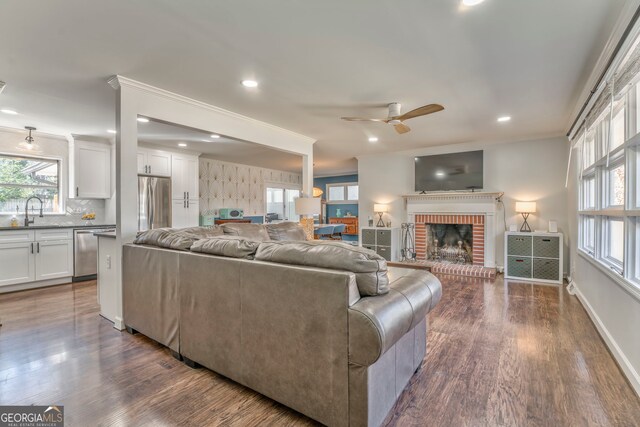 living room with dark wood finished floors, a fireplace, and crown molding