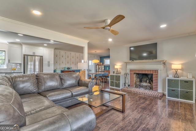 living area with dark wood-style floors, a fireplace, crown molding, recessed lighting, and a ceiling fan