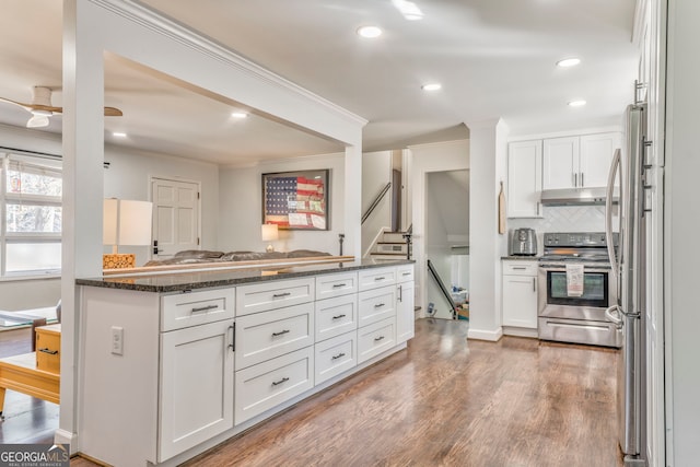 kitchen with stainless steel appliances, dark stone countertops, and white cabinetry