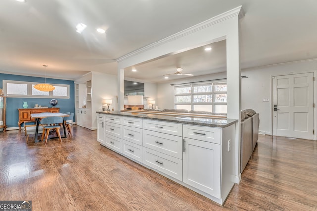 kitchen with hanging light fixtures, wood finished floors, and white cabinets