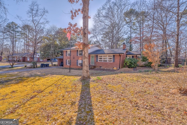 view of front of home with crawl space, a front yard, a chimney, and brick siding