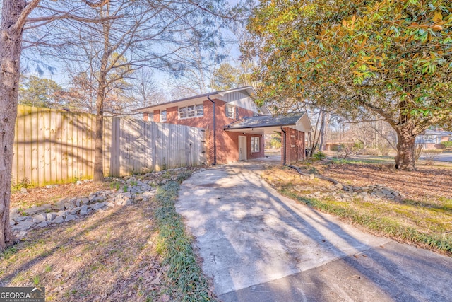 view of front of home featuring driveway, fence, and brick siding
