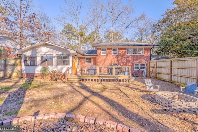 back of house with an outdoor fire pit, a sunroom, fence, and a deck