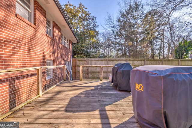 wooden terrace featuring a fenced backyard and a grill