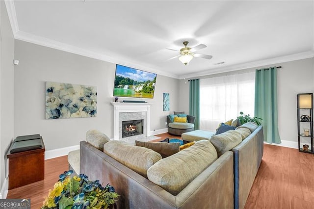 living area with a ceiling fan, a fireplace, crown molding, and wood finished floors